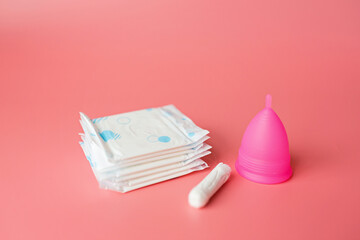 Menstrual cup, sanitary pad, tampon on pink background. Alternative feminine hygiene product during the period. Women health concept. Copy space. Eco friendly concept, zero waste product. Flat lay