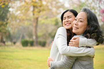 Obraz premium Lovely Asian granddaughter spending time with her grandmother, giving a big hug