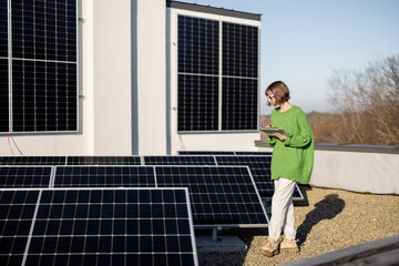 Young woman with a digital tablet monitors energy production from the solar power plant on rooftop...