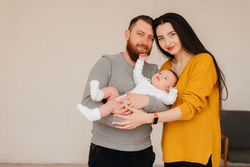 Smiling mother and father holding their newborn baby son at home