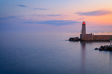 Fototapeta na wymiar Mediterranean Sea with the lighthouse at sunset in the harbor, Nice, France