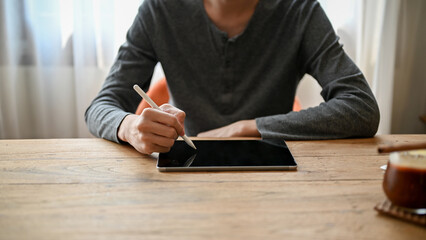 Cropped image of smart Asian man using digital tablet while relaxing in the cafe.