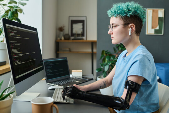 Young IT specialist with prosthetic arm concentrating on her online work, she working with security codes