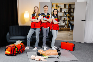Group of people with cpr dummy looking at camera and smiling after first aid training class