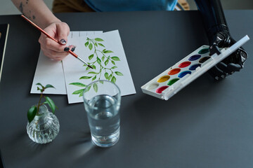 High angle view of woman with prosthetic hand painting picture with paints and brush