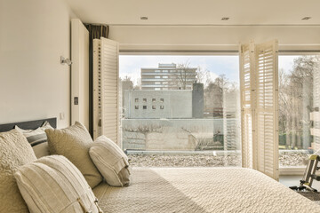 a bedroom with white walls and wooden shutters on the sliding glass door that leads to an outside...