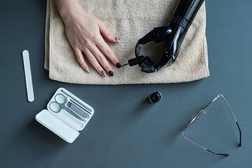 High angle view of young woman with prosthetic arm painting her nails with varnish