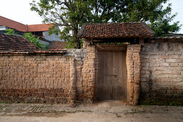 Fototapeta na wymiar Old aged house entrance and wall made of laterite in Duong Lam ancient village, Son Tay district, Hanoi, Vietnam