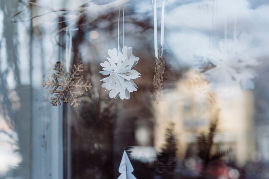 snowflake in window of shop with sunlight & lights in winter christmas