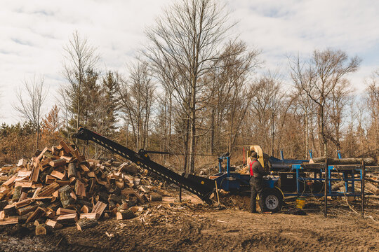 man splitting wood into wood pile with wood processor