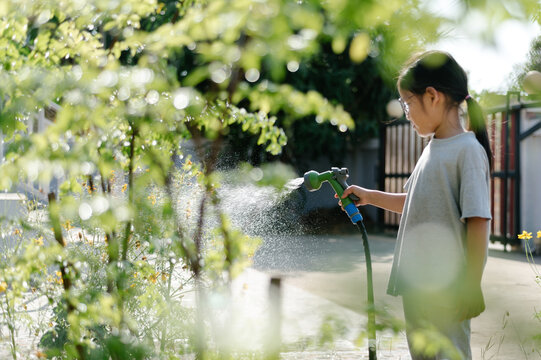 Girl Watering Plants In Garden