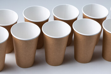 Disposable cardboard biodegradable cups on a white table, gray background.