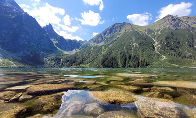 Mountains and river, view from the lower angle, you can see the stones in the water and beautiful clouds in the light of the sun