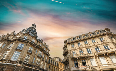 Fototapeta na wymiar Low-angle view of tall luxury haussmannian buildings - French city with renovation scaffoldings - construction renovation - dramatic sky