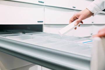 Close up of pharmacist hand taking medicine from drawer	
