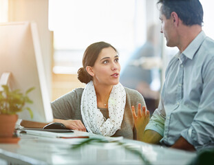 He has a lot of advice to offer. designers talking together at a workstation in an office.