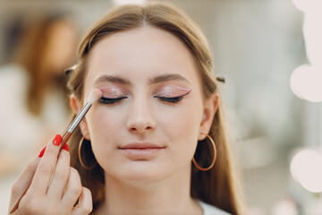 Beautiful young woman applying makeup beauty visage brush.