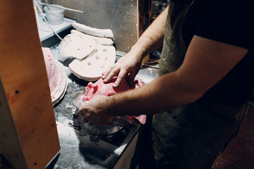 Artisan craftsman create mask based on plaster cast. Gypsum mold and plastic mask sculpting.