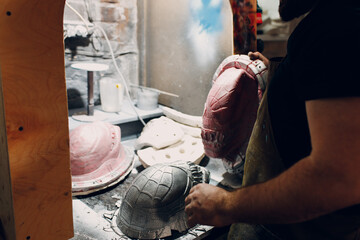 Artisan craftsman create mask based on plaster cast. Gypsum mold and plastic mask sculpting.