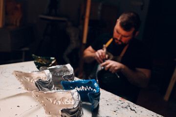 Artisan craftsman create mask based on plaster cast. Gypsum mold and plastic mask sculpting.