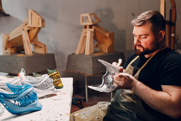 Artisan craftsman create mask based on plaster cast. Gypsum mold and plastic mask sculpting cutting knife