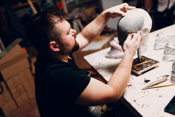 Artisan craftsman create mask based on plaster cast. Gypsum mold and plastic mask sculpting.