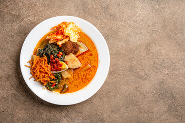 Lontong sayur or vegetable rice cake is an Indonesian traditional rice dish made of pieces of lontong served in coconut milk soup with shredded chayote, tempeh, tofu, hard-boiled egg, sambal, rendang