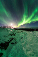 Fototapeta na wymiar imagen de un paisaje nevado con una aurora boreal iluminando el cielo nocturno de Islandia con estrellas de fondo
