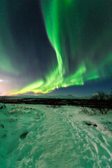 imagen de un paisaje natural nocturno nevado, con una aurora boreal en el cielo nocturno de Islandia  - obrazy, fototapety, plakaty