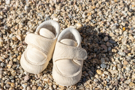 赤ちゃんの靴とたくさんの小石。靴に小石が入るイメージ