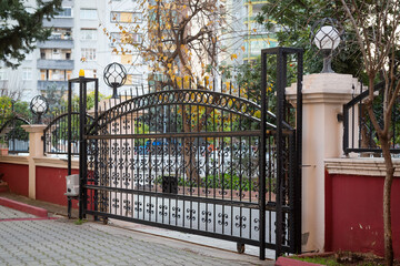 Metal garden gate that can be opened automatically with a remote control. Decorative carriage door decorated with spear-tipped iron bars.
