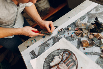 Fototapeta na wymiar Craftsman cutting smalt glass with nippers cutters for making smalt glass mosaic