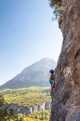 Child rock climber. The boy climbs the rock. The child is engaged in rock climbing on natural...