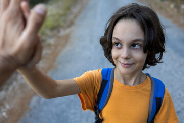 Naklejka premium boy with a backpack gives five. The child enjoys spending time with their parents.