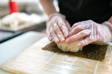 professional chef's hands making sushi roll in a restaurant kitchen
