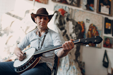Male musician playing banjo sitting chair indoor.