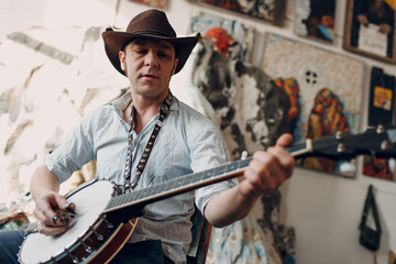 Male musician playing banjo sitting chair indoor.