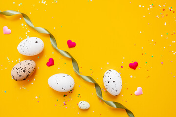 beautiful festive layout of confetti and easter eggs on a bright yellow background. top view. copy space. flat lay
