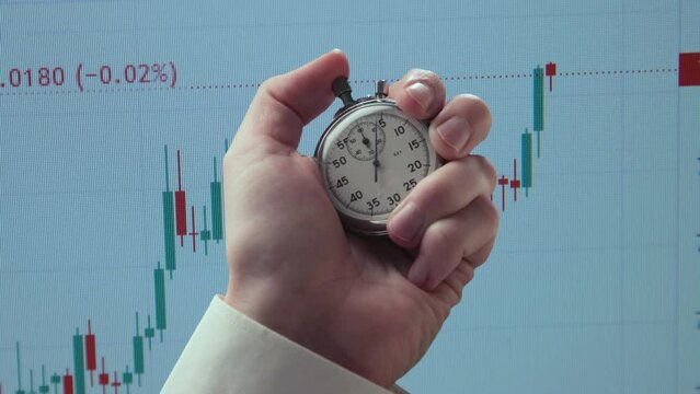 Stopwatch in a hand against background of chart
