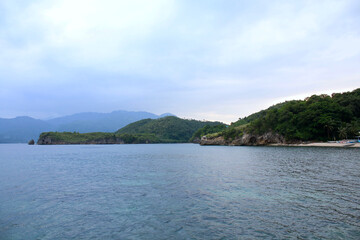 Fototapeta na wymiar View of a hilly tropical island and a calm sea.