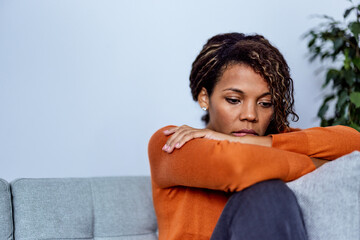 Adult African woman suffering from depression, sitting alone at home.