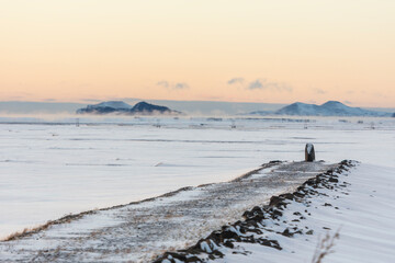 imagen de un camino sobre un paisaje nevado con las montañas de fondo y el cielo azul