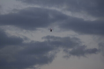Rainy Clouds. A helicopter in a rainy cloudy sky covering the sun. Clouds Covering Sky.