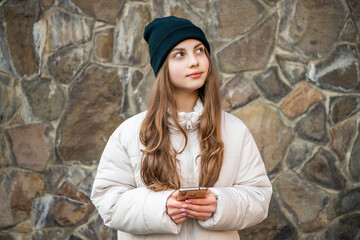 dreamy teen girl blogging on phone at stone background. teen girl blogging