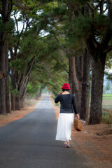 Fototapeta premium a female traveler holds a vintage suitcase and walks under a 100-year-old ancient pine