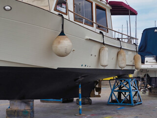 White fishing boat beached at port dock marina for hull paint
