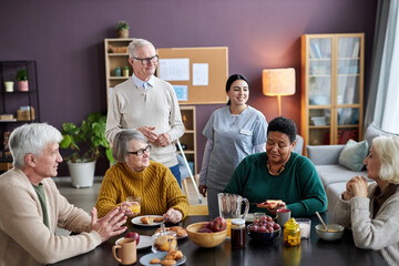 Breakfast scene in retirement home with group of smiling senior people