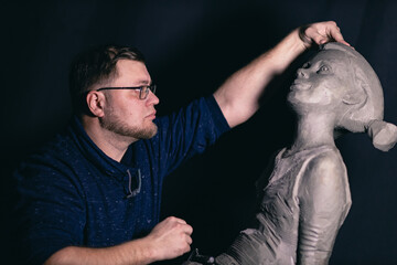 Man sculptor creates sculpt bust clay human woman sculpture. Statue craft creation workshop.