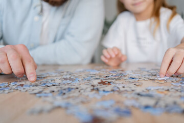 Cropped image family playing with puzzle on table at home together.