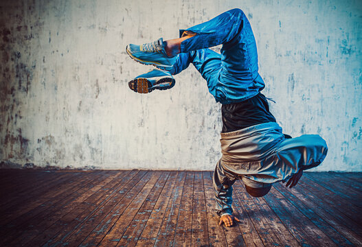 Young man break dancing on wall background